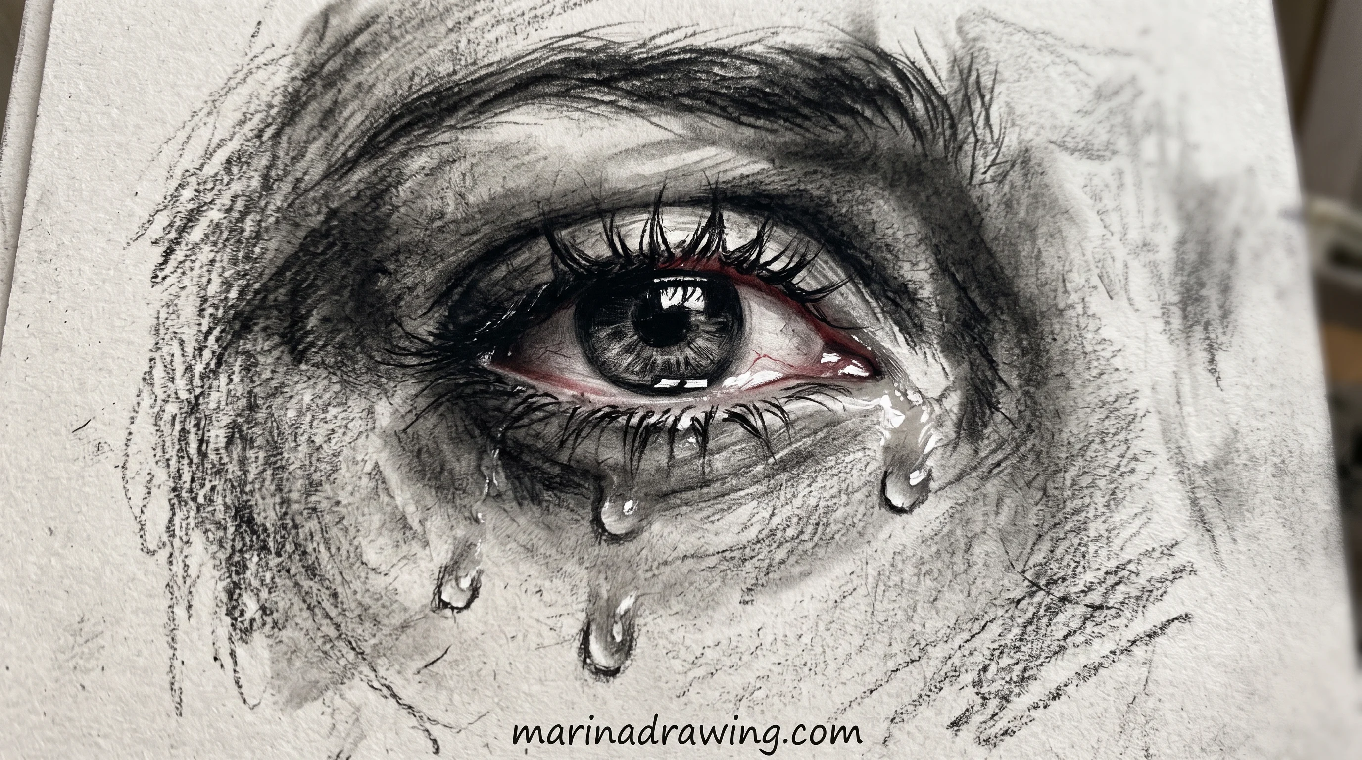 Charcoal sketch of a crying eye with visible tear